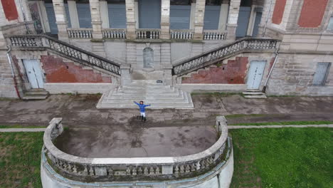 Young-dancer-doing-a-front-flip-over-steps-aerial-drone-view
